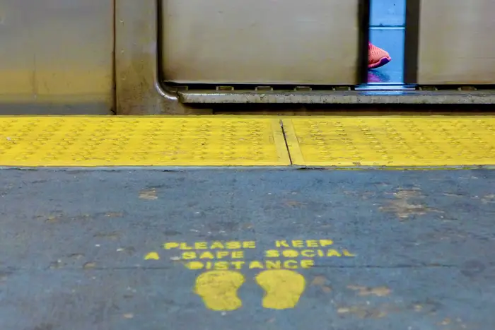 A photo of a social distance message on ground of subway platform